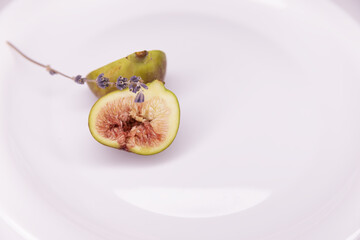 Cut figs with a sprig of lavender on a glossy white background. Copy space