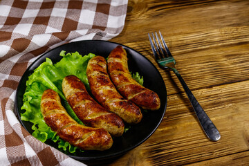 Tasty grilled sausages on a wooden table