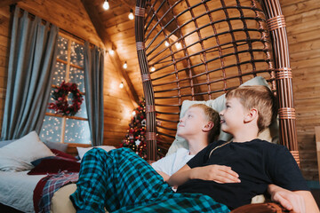 Obraz na płótnie Canvas children two boys sit in a hammock in a Christmas interior