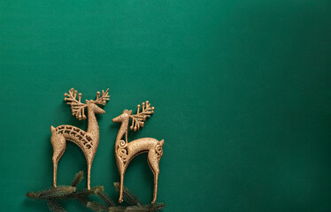 couple of christmas golden reindeers against dark green background 