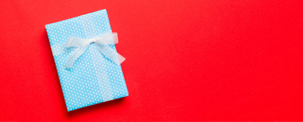 Top view Christmas present box with white bow on red background with copy space