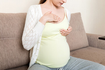 pregnant girl checks her breasts. prevention of breast cancer
