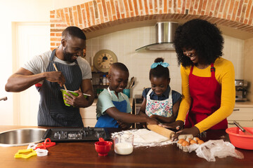African american family wearing apron baking together in the kitchen at home