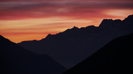 Breathtaking sunset with dramatic sky and silhouettes of mighty snow-capped mountains in the Himalaya viewed from Sherpa village Dingboche (4,340 m) in Khumbu region, Sagarmatha National Park, Nepal.