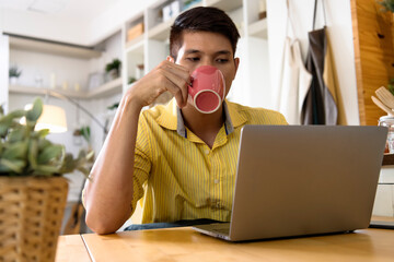 Business man sipping coffee while looking at laptop computer.