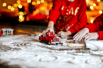 Children's hands making cookies on the table with torment against Christmas back