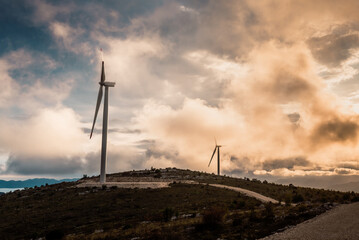 Wind turbines on beautiful cloudy summer autumn sunset. Mountain landsape. Green ecological power...