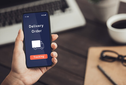 Modern devices, purchase and delivery. Woman at workplace at home office with laptop checks smartphone