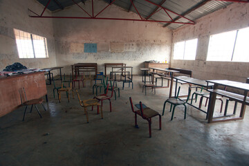 wide angle horizontal photography of  an African school classroom with white walls, bright windows and many empty wooden and metal chairs, in the Gambia . Africa with natural light