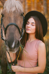 Obraz premium Girl in a hat sits on a horse in nature.