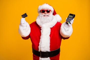 Fototapeta na wymiar Portrait of his he nice attractive cheerful fat Santa holding in hand bank card digital terminal safe shopping system commerce trade isolated bright vivid shine vibrant yellow color background