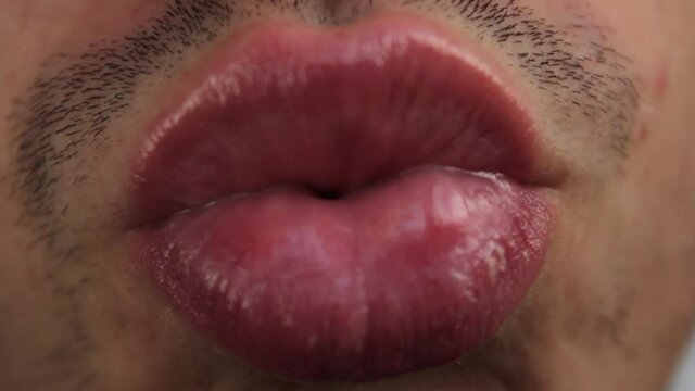 Young Caucasian man with lips shiny from balm kisses the lens of the camera. Funny emotions for Valentine's Day. The 14th of February.