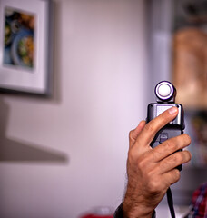 Hand held light meter isolated in studio lights.. A hand is holding a light meter against black background.