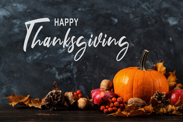 Thanksgiving greetings. Dry yellow leaves, pumpkins, berries, nuts and frame on a wooden background, top view. Kaligraphic capital inscription.