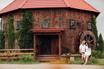 Couple in love walks near a large wooden mill on summer day. man and woman are having fun outdoors.