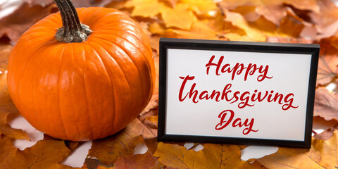 Thanksgiving greetings. Dry yellow leaves, pumpkins and frame on a white background, top view. Kaligraphic capital inscription.
