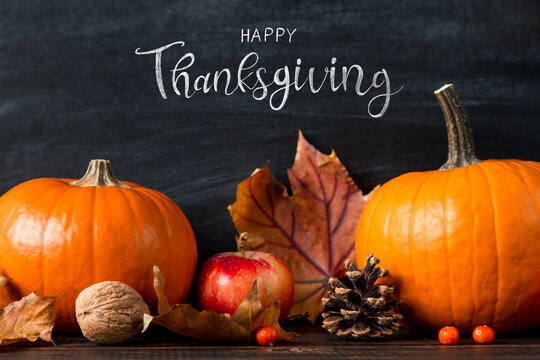 Thanksgiving greetings. Pumpkin, leaves, apples on a chalkboard background, top view. Kaligraphic capital inscription.
