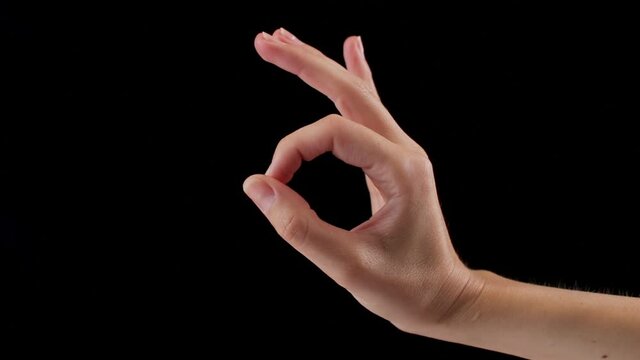 Woman's hand showing OK sign, okay gesture isolated on black background in studio