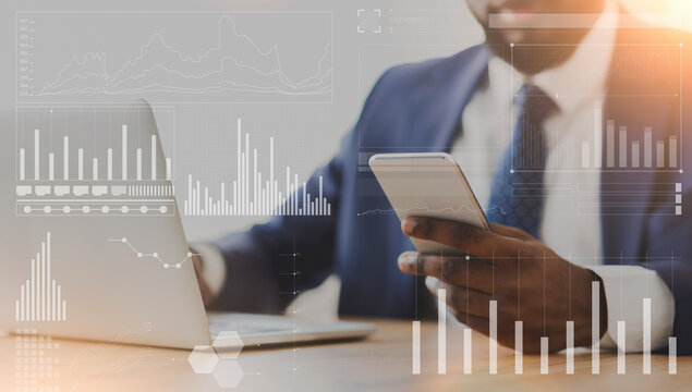 African American businessman using cellphone and laptop at workplace, collage with company analytics on imaginary screen