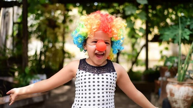 Little Brazilian girl dressed as a clown and playing happily, blurred background, selective focus.