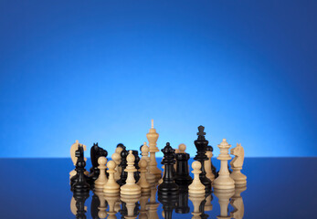 Black and white chess pieces standing together on blue gradient background. Team work concept.