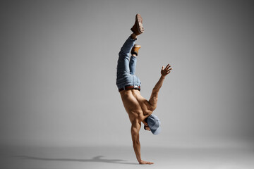 Topless muscualr man in jeans doing a handstand