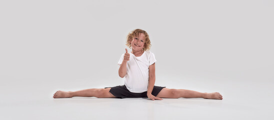 Full length shot of little playful boy child smiling at camera, showing thumbs up while doing...