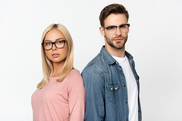 Couple in eyeglasses looking at camera while standing isolated on grey
