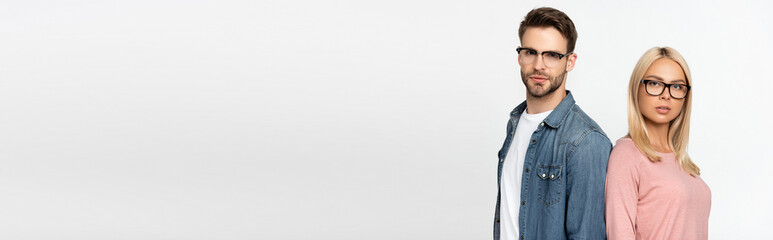 Couple in eyeglasses looking at camera isolated on grey, banner