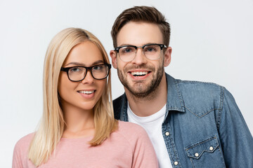 Blonde woman in eyeglasses smiling at camera near boyfriend isolated on grey