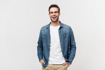 Positive man in eyeglasses holding hands in pockets of pants and looking away isolated on grey