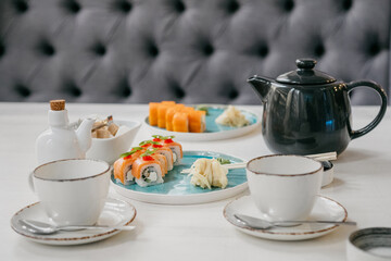 Philadelphia rolls on a white plate with soy sauce and ginger