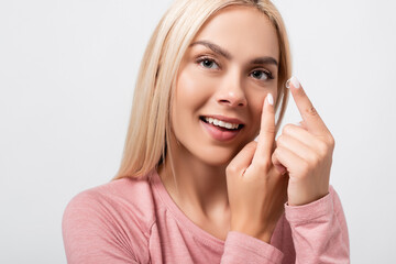 Smiling blonde woman wearing contact lens isolated on grey