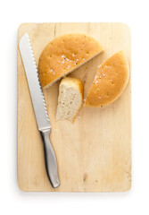 Top view of fresh sliced focaccia and knife on wooden cutting board, isolated on white background.