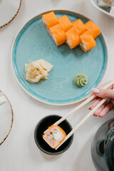 Philadelphia rolls on a white plate with soy sauce and ginger