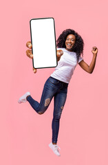 Excited black lady holding smartphone, jumping up