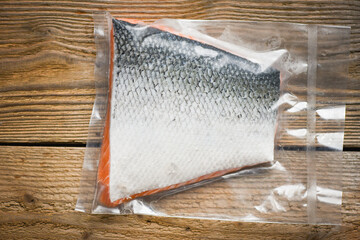 Salmon fillet packaged in plastic vacuum pack in packing sell in supermarket - Fresh raw salmon fish steak on wooden background