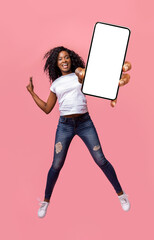 Happy african woman showing empty smartphone screen while jumping up