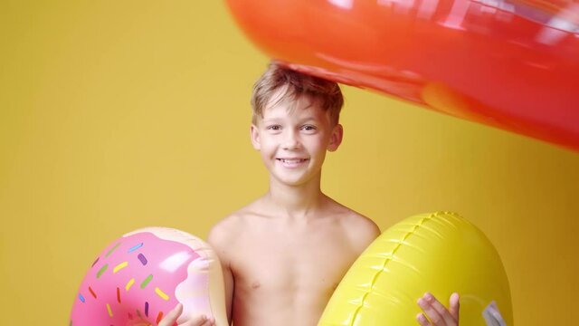 Cute little boy with different inflatable rings on color background