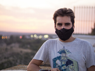 Young European male with a medical mask and the beautiful sunset in the background - the new normal