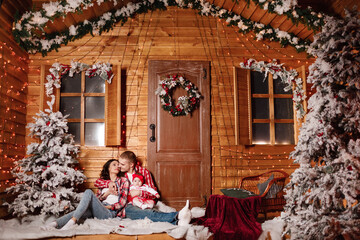 Obraz na płótnie Canvas Happy family at Christmas eve sitting together near decorated tree at living room, home. Father, mother and baby girl. Concept of celebrating New Year holiday