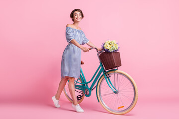 Photo portrait of cute woman holding bicycle with two hands isolated on pastel pink colored...