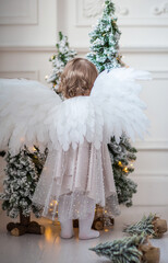 child with angel wings by the christmas tree