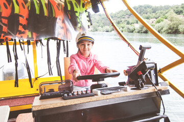 Smiling portrait of little girl with a captain cap on river boat.