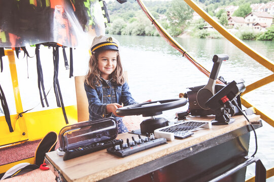 Smiling portrait of little girl with a captain cap on river boat.