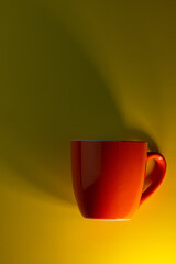 orange cup and dark shadow on a yellow background. Business concept.