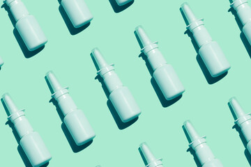 White medical nasal spray bottle on aqua mint background pattern flat lay with harsh shadow...