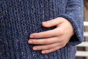 Girl's hand on soft warm dark blue knitted sweater. Autumn soon