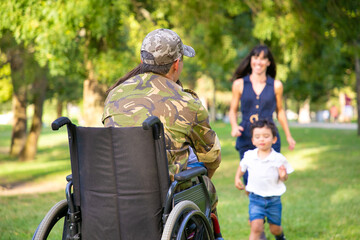 Two happy kids and their mom running toward disabled retired military father and hugging him....