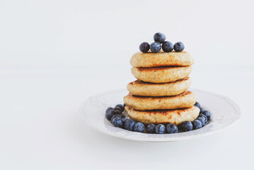 Stack of homemade small thick pancakes served with fresh blueberries.